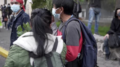 A-man-and-a-woman-are-holding-green-leaves-and-a-stick-while-wearing-masks-during-the-march-in-International-Women's-Day-in-Quito