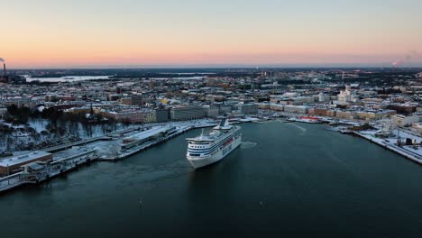 Vista-Aérea-Del-Crucero-De-La-Línea-Silja-Saliendo-De-Helsinki,-Durante-La-Puesta-De-Sol-De-Invierno---Dando-Vueltas,-Disparo-De-Drones