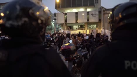 Policemen-with-their-helmets-on-are-standing-in-front-of-a-group-of-women-who-march-during-a-protest-in-the-International-Women's-day-in-Quito,-Ecuador