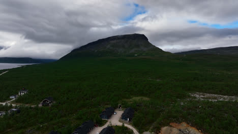 Vista-Aérea-Ascendiendo-Frente-A-Un-Resort-Con-La-Saana-Caída-Al-Fondo,-Nublado,-Día-De-Verano-En-Kilpisjarvi,-Finlandia