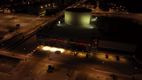 Aerial-view-orbiting-the-illuminated-Oulu-Theatre,-winter-evening-in-Finland