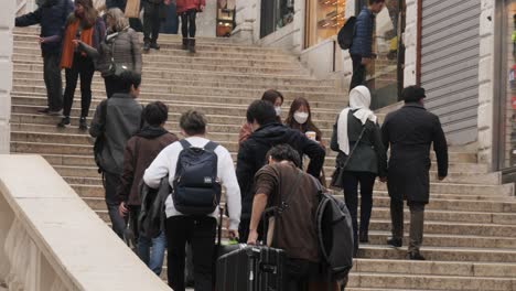 Two-young-attractive-asian-women-wearing-protective-masks-and-holding-fast-food,-walking-down-the-stairs-of-Rialto-Bridge-in-Venice-after-the-cancelled-Carnival