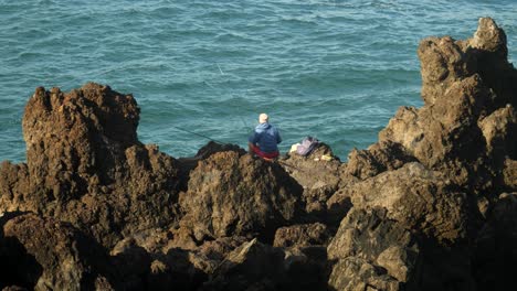 Fischer-Sitzt-Auf-Felsen-In-Puerto-De-La-Cruz