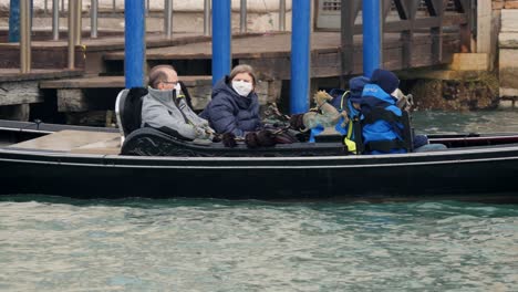 Familia-Sentada-En-Una-Góndola-Con-Máscaras-Protectoras-Un-Día-Después-De-La-Cancelación-Del-Carnaval-De-Venecia,-Debido-Al-Brote-De-Coronavirus