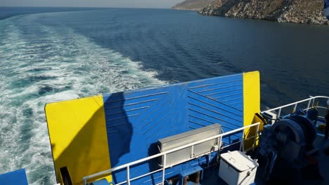 Parte-Trasera-De-Un-Ferry-Con-Bandera-Griega-Y-Su-Sombra-Ondeando