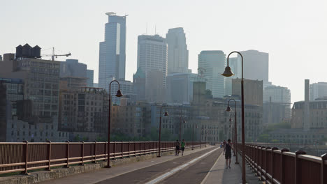 Fußgänger-über-Der-Steinbogenbrücke-Bei-Sonnenaufgang-In-Minneapolis,-Minnesota,-USA