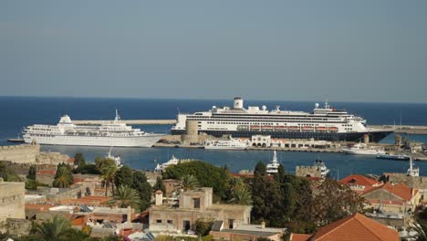 Vista-Panorámica-Del-Puerto-En-El-Casco-Antiguo-De-Rodas,-Edificios-Y-árboles-Verdes-En-Primer-Plano,-Cruceros-Y-Barcos-Al-Fondo