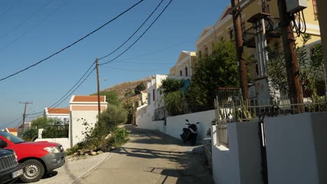 Típica-Calle-Estrecha-Y-Vacía-En-La-Isla-Symi,-Autos-Estacionados-Al-Costado-De-La-Carretera