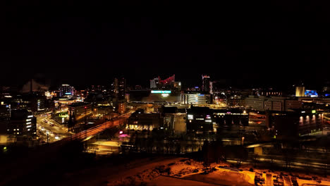 Aerial-view-approaching-the-night-lit-Nokia-arena,-winter-evening-in-Tampere,-Finland