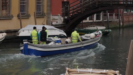 Workers-in-yellow-hi-viz-on-a-boat-in-the-canal-of-Venice-after-the-cancelled-Carnival