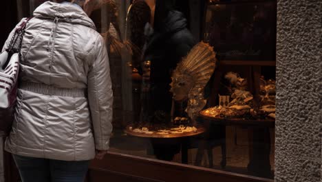 Lady-watching-a-decorative-carnival-masque-through-the-shop-window,-after-the-cancelled-carnival