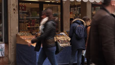 Two-young-women-at-a-store-in-Venice,-after-the-cancelled-Carnival,-Two-man-in-protective-masks-walks-by