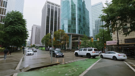 Verkehr-Und-Fußgänger-Auf-Nasser-Stadtstraße-An-Einem-Regnerischen-Tag-In-Vancouver,-Kanada