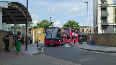 Dos-Autobuses-Rojos-De-Londres-Atraviesan-El-Paso-De-Peatones-En-La-Estación-De-Tren-De-Lewisham,-Al-Sureste-De-Londres