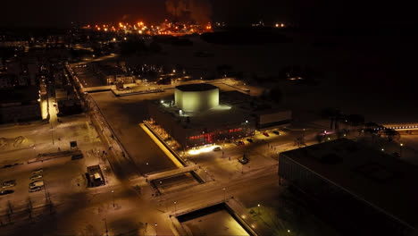 Volando-Alrededor-Del-Teatro-Iluminado-De-Oulu,-Noche-De-Invierno-En-Finlandia---Vista-Aérea