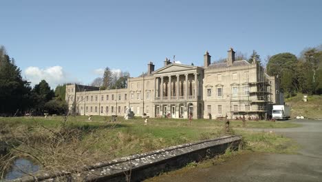 Low-angle-aerial-tracking-over-a-bridge-towards-Glynllifon-mansion