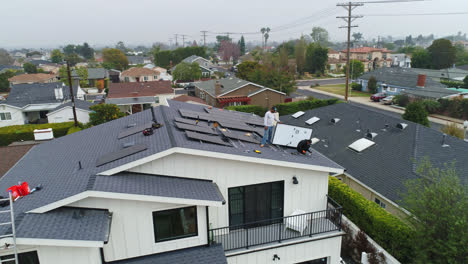 Aerial-view-around-technicians-installing-sun-panels-on-top-of-a-house---orbit,-drone-shot