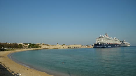 Rhodos-Hafen-Mit-Großen-Kreuzfahrtschiffen-Vor-Anker,-Sandstrand-Und-Den-Mauern-Der-Altstadt-Im-Hintergrund