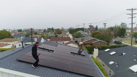 Vista-Aérea-De-Hombres-Instalando-Células-Fotovoltaicas-En-Un-Tejado---Descendiendo,-Disparo-De-Drone