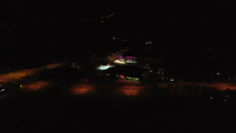 Aerial-view-of-the-Jounin-kauppa-market-and-shopping-center,-winter-night,-in-Akaslompolo,-Finland---tracking,-drone-shot