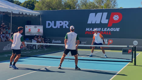 Male-athletes-playing-an-intense-pickleball-match-and-scoring-a-point,-in-Sunny-Newport-Beach,-California,-USA---Handheld