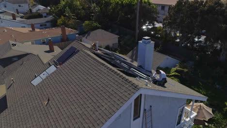 órbita-Aérea-Alrededor-De-La-Azotea-Con-Trabajadores-Instalando-Y-Realizando-Mantenimiento-En-Múltiples-Paneles-Solares-En-Un-Día-Soleado-En-Los-ángeles,-California---órbita,-Disparo-De-Drones