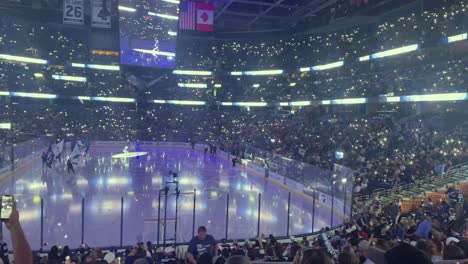 Jugadores-De-Tampa-Bay-Lightning-Entrando-Al-Hielo-Al-Comienzo-De-Un-Juego-En-Una-Pista-Cubierta-De-Hockey-Sobre-Hielo-Con-Las-Luces-Apagadas-Y-La-Multitud-Vitoreando