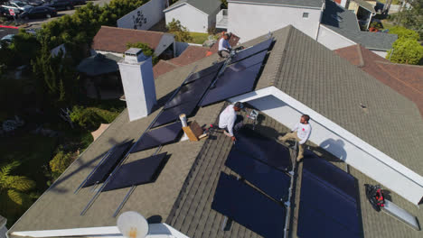 órbita-Aérea-Alrededor-De-Tres-Trabajadores-En-Una-Azotea-Están-Instalando-Y-Realizando-Mantenimiento-En-Paneles-Solares-Los-Angeles,-California---órbita,-Disparo-De-Drones