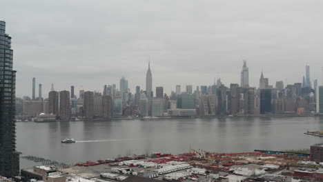 Panorámica-Lenta-En-El-Horizonte-Del-Centro-De-La-Ciudad-De-Nueva-York-Y-El-Edificio-Empire-State-Desde-La-Zona-Industrial-En-Un-Día-Nublado-Corrección-De-Color-Neutro