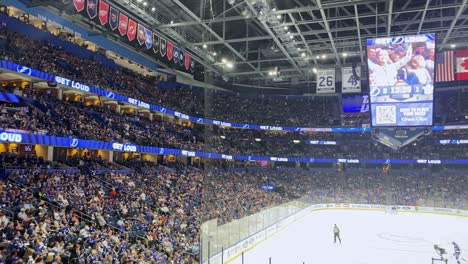 Aficionados-Al-Hockey-Sobre-Hielo-Animando-Durante-El-Partido-En-Una-Pista-De-Hielo-Cubierta.