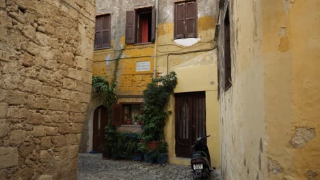 Casas-Tradicionales-Pintadas-De-Amarillo,-Muro-De-Piedra-Y-Camino-Rocoso-En-El-Casco-Antiguo-De-Rodas.