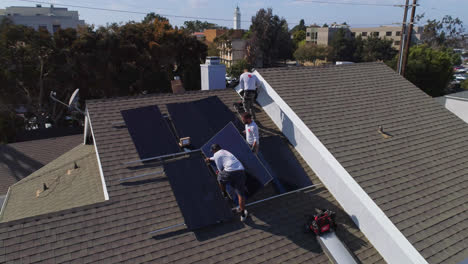 órbita-Aérea-Lenta-Alrededor-De-Tres-Trabajadores-En-Una-Azotea-Instalando-Y-Realizando-Mantenimiento-De-Paneles-Solares-Los-Angeles,-California---órbita,-Disparo-De-Drones