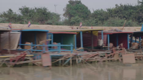 Barcos-Adornados-Sobre-Un-Río-Por-La-Aldea-De-Kampong-Phluk-Con-Casas-Sobre-Pilotes