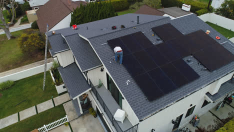 Vista-Aérea-Del-Hombre-Instalando-Paneles-Solares-En-La-Azotea-De-Una-Casa-Suburbana.