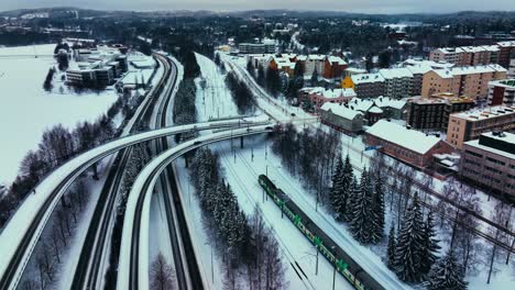 Vista-Aérea-Alrededor-De-Un-Tren-Que-Sale-De-La-Ciudad-De-Jyvaskyla,-Noche-De-Invierno-En-Finlandia---Dando-Vueltas,-Disparo-De-Drone