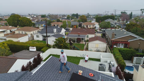 Vista-Aérea-De-Los-Técnicos-Que-Realizan-El-Mantenimiento-De-Generadores-De-Energía-Solar-En-La-Parte-Superior-De-Una-Casa---Reversa,-Disparo-De-Drones