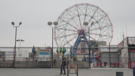 Wonder-wheel-and-people-wearing-face-mask-on-boardwalk-in-Coney-Island