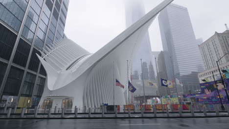 Leerer-Bürgersteig-Vor-Dem-Oculus-An-Einem-Regnerischen-Tag-Mit-Amerikanischer-Flagge,-Die-In-Zeitlupe-Weht