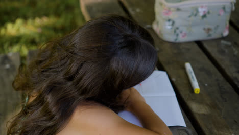 Girl-drawing-on-a-picnic-table