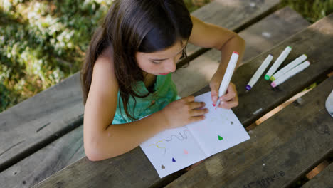 Girl-drawing-on-a-picnic-table