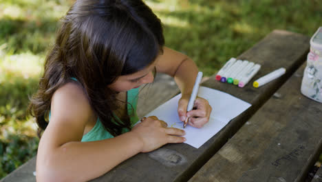 Girl-drawing-on-a-picnic-table