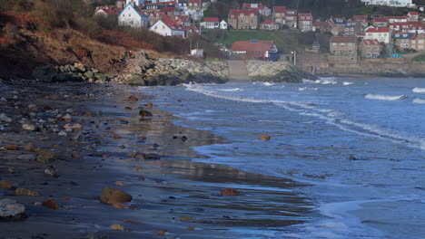 Low-Drone-Shot-over-Beach-with-Elderly-Couple-with-Dogs-Walking-Runswick-Bay