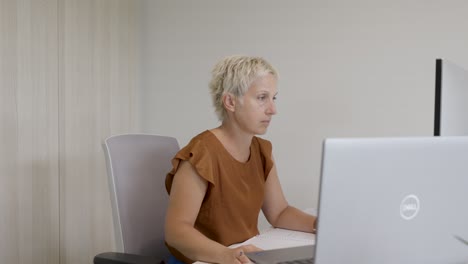 Slow-revealing-shot-of-a-buisness-woman-working-at-her-desk-during-a-busy-day