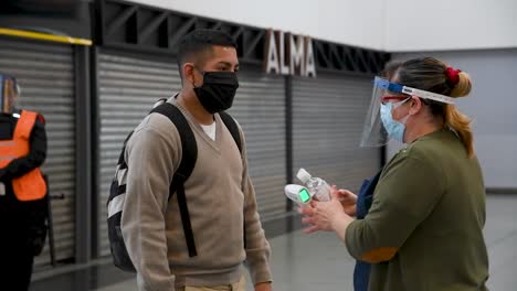 Public-health-worker-stops-commuter-at-train-station-and-shakes-hand-sanitizer-into-hands