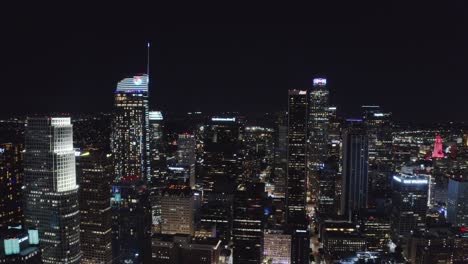 Rascacielos-Del-Centro-De-Los-Angeles-Ca-Por-La-Noche,-Vista-Aérea-De-Torres-Y-Calles-Iluminadas