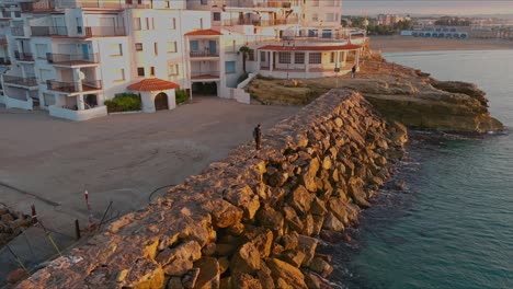 Tourist-Steht-Zur-Goldenen-Stunde-Auf-Einem-Felsigen-Pier-Im-Dorf-Roc-De-Sant-Gaieta