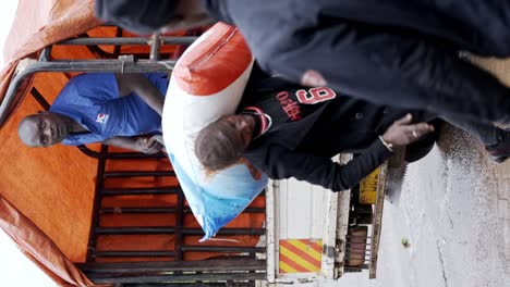 Men-Unloading-Animal-Feed-on-a-Farm-in-Kenya,-East-Africa---Vertical-Shot