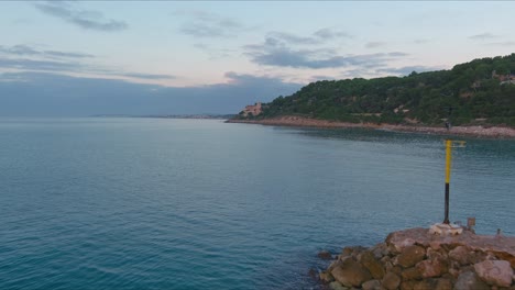 Drone-captures-tourist-on-rocky-pier-at-Roc-de-Sant-Gaieta,-Tarragona