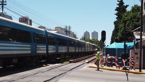 Slow-Motion-Public-train-cross-tracks,-security-agent-works,-man-in-a-wheelchair-Sarmiento-Line