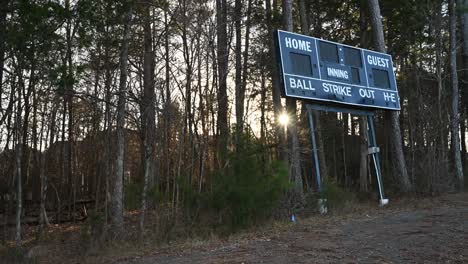 Charlotte,-Carolina-Del-Norte,-Estados-Unidos---14-De-Enero-De-2024:-Puesta-De-Sol-En-Timelapse-A-Través-De-Los-árboles-Mirando-Un-Viejo-Marcador-De-Béisbol